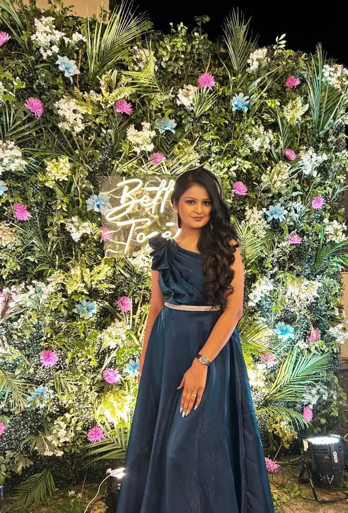 Anupriya Tripathi in a navy gown against a flower wall