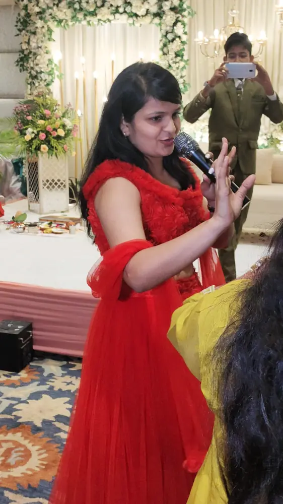 Anupriya Tripathi speaking into a microphone in a red gown
